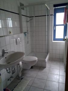 a bathroom with a sink and a toilet and a shower at Moderne Ferienwohnung mit Balkon in Strandnähe in Friedrichskoog