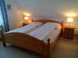 a wooden bed in a bedroom with two lamps at Moderne Ferienwohnung mit Balkon in Strandnähe in Friedrichskoog +14 photos