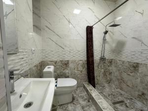 a white bathroom with a toilet and a sink at Hello Dushanbe Hostel in Dushanbe