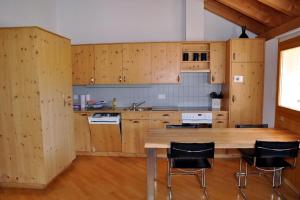 een keuken met houten kasten en een houten tafel bij Suotchalchera 5 in Ftan