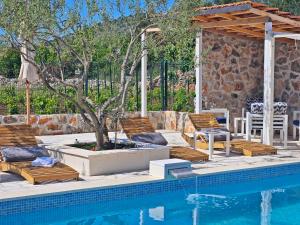 ein Pool mit Stühlen und ein Baum neben einem Haus in der Unterkunft Flamingo - House with private pool in Gornji Seget
