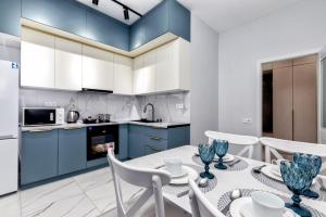 a kitchen with blue cabinets and a table and chairs at 2 room apartament Barys arena in Astana