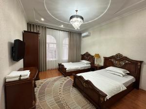 um quarto com 2 camas, uma televisão e um lustre em Hello Dushanbe Hostel em Dushanbe