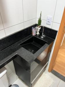 a kitchen sink with a black counter top at Quarto vip in Uberaba