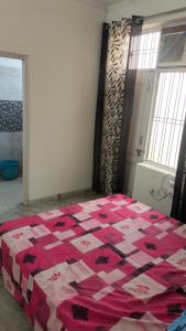 um quarto com uma colcha vermelha e branca numa cama em Bagpacker Stay em Faridabad