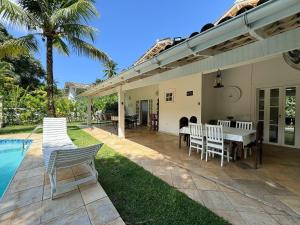 a patio with a table and chairs next to a pool at Casa com piscina privativa a 100m da Praia de Paúba in São Sebastião