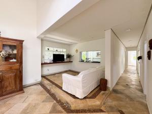 a living room with a white couch and a tv at Casa com piscina privativa a 100m da Praia de Paúba in São Sebastião