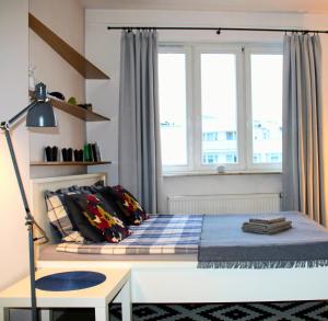 a bedroom with a bed with a desk and two windows at Apartament blisko Centrum in Warsaw