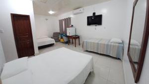 Cette chambre comprend 2 lits et une télévision. dans l'établissement Pousada Muiraquitã Parintins, à Parintins