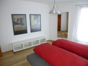 een woonkamer met een rode bank en foto's aan de muur bij Craista 5 in Scuol