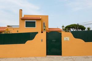 a orange house with a green gate and a fence at Casa do Vale in Chelreira