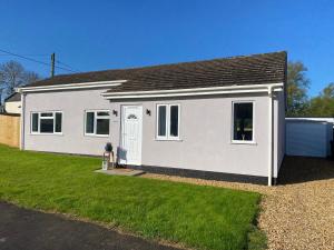 a white house with a grass yard at Blossom Lodge - Detached bungalow near Kings Lynn in Narborough