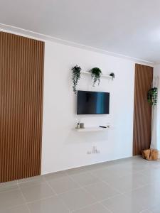 uma sala de estar com televisão numa parede branca em Apartamento a pasos de la playa em Punta Cana