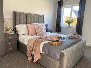 um quarto com uma cama grande e uma cabeceira cinzenta em Blossom Lodge - 3 Bedroom Bungalow in Norfolk Perfect for Families and Groups of Friends em Narborough
