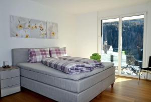 ein Bett mit einer Decke in einem Zimmer mit einem Fenster in der Unterkunft Chasa Miramunt 2 in Scuol