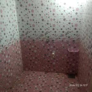 a bathroom with a shower with a wall covered in polka dots at Dwarka Home Stay 2 Only family in Dwarka