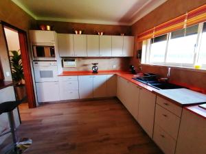 una cocina con armarios blancos y encimeras rojas en Casa do Vale, en Chelreira