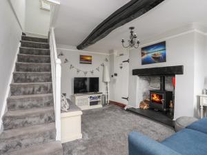 a living room with a staircase and a fireplace at Tan Yr Allt in Pwllheli
