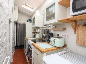 a small kitchen with a stove and a microwave at Tan Yr Allt in Pwllheli