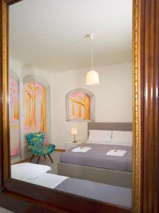 uno specchio che riflette una camera da letto con un letto e una sedia di Affittacamere di Andrea Bertolino San Lazzaro di Savena a San Lazzaro di Savena