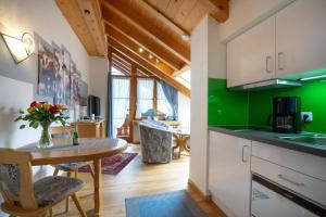 eine Küche mit grünen Wänden sowie einem Tisch und Stühlen in der Unterkunft Landhaus Barbara Ferienwohnungen in Oberstdorf