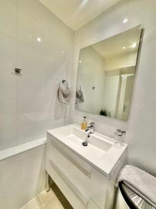 La salle de bains blanche est pourvue d'un lavabo et d'un miroir. dans l'établissement Residence Mont-Blanc, à Genève