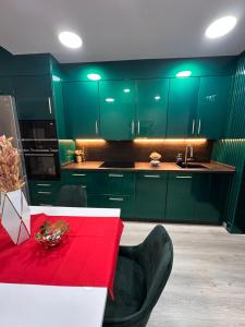 une cuisine avec des placards verts et une table rouge dans l'établissement APARTAMENTO CERCA AL MAR, à Benalmádena