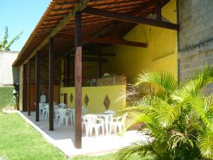 a patio with white tables and chairs on a yellow building at Sitio do Popay in Rio de Janeiro