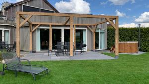 un pavillon avec des chaises et des tables dans une cour dans l'établissement Villa Riverside met hottub, eigen aanlegsteiger, zwemtrap, trampoline en kano's, à Zeewolde