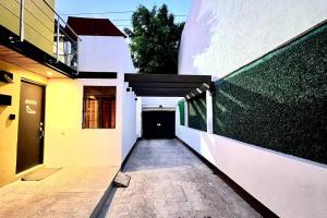 einen Flur eines weißen Gebäudes mit einer schwarzen Tür in der Unterkunft Maranello - Exclusive Suite Guadalupe Inn in Mexiko-Stadt