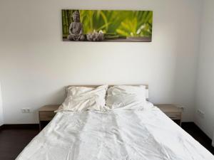 een bed met witte lakens en een foto aan de muur bij Vila Bösdorf Apartments in Rätzlingen