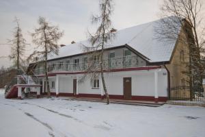 a white house with a balcony in the snow at U Gienka Pod Lasem in Święta Katarzyna