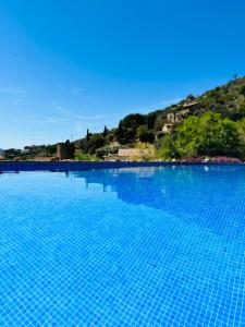 ein großer blauer Pool mit einem Hügel im Hintergrund in der Unterkunft B&B La Vista Brava in Platja  d'Aro
