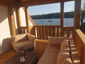 ミコワイキにあるDom nad jeziorem Mikołajkiのソファと椅子付きのポーチから水辺の景色を望めます。