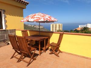 una mesa y sillas con una sombrilla en el balcón en Big Room at Villa Lila, en Puerto de la Cruz