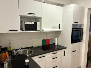 a kitchen with white cabinets and a sink and a microwave at Anna's Apartment 4 Personen in Wiesbaden