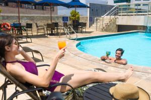 two people sitting in chairs in a pool with drinks at Hotel Atlante Plaza in Recife