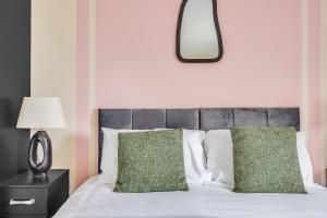 een slaapkamer met een bed met groene kussens en een spiegel bij 3 Bed House - Contractors, Relocators & Visitors, Coffee Machine & Free Parking in Bedford