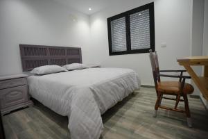 a bedroom with a bed and a desk and a chair at Un ton Violet in Sfax