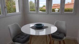 einem weißen Tisch mit zwei Stühlen und einer Schüssel darauf in der Unterkunft Sparsames Solar-Ferienhaus mit Meerblick, AC und Heizung in Muntanya la Sella