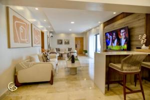Una sala de estar con un sofá y un televisor. en Golden Penthouse by Amar'e, en Las Terrenas