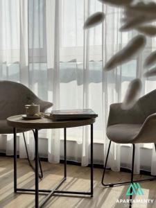 a coffee table and two chairs in front of a window at APARTAMENTY SZYNDZIELNIA ROWERY GÓRY Spacery in Bielsko-Biala