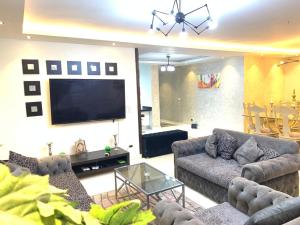 uma sala de estar com sofás e uma televisão de ecrã plano em شقه فندقية للإيجار بالشيخ زايد em Sheikh Zayed