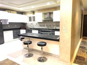 a kitchen with a black counter and two stools at شقه فندقية للإيجار بالشيخ زايد in Sheikh Zayed