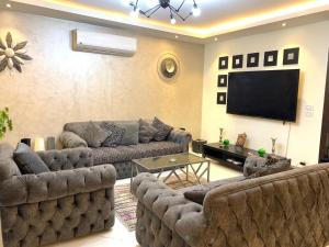 uma sala de estar com sofás e uma televisão de ecrã plano em شقه فندقية للإيجار بالشيخ زايد em Sheikh Zayed