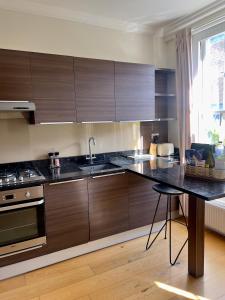 a kitchen with wooden cabinets and a black counter top at Homely One Bedroom Apartment in London