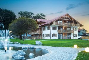 une grande maison avec un étang en face de celle-ci dans l'établissement Landgasthof Schmuck, à Sauerlach