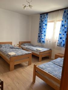 three beds in a room with blue curtains at Cheap house near the center of the city in Mostar
