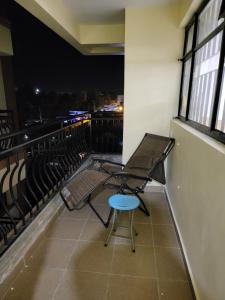 un fauteuil et un tabouret sur un balcon la nuit dans l'établissement G&G Homes Executive Suite, à Nakuru