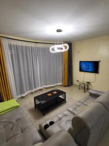 Il comprend un salon doté d'un canapé et d'une télévision à écran plat. dans l'établissement G&G Homes Executive Suite, à Nakuru